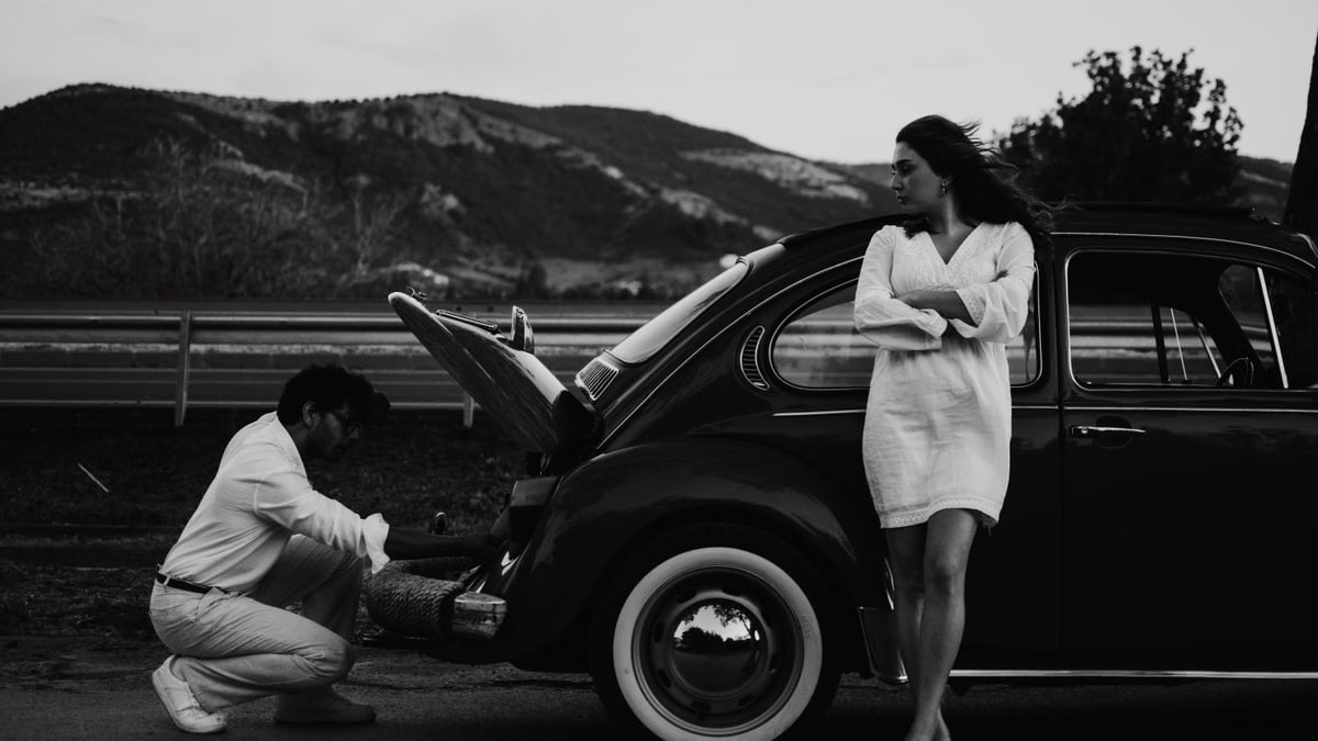 A couple with a vintage Volkswagen on a scenic road in Çanakkale, Türkiye.